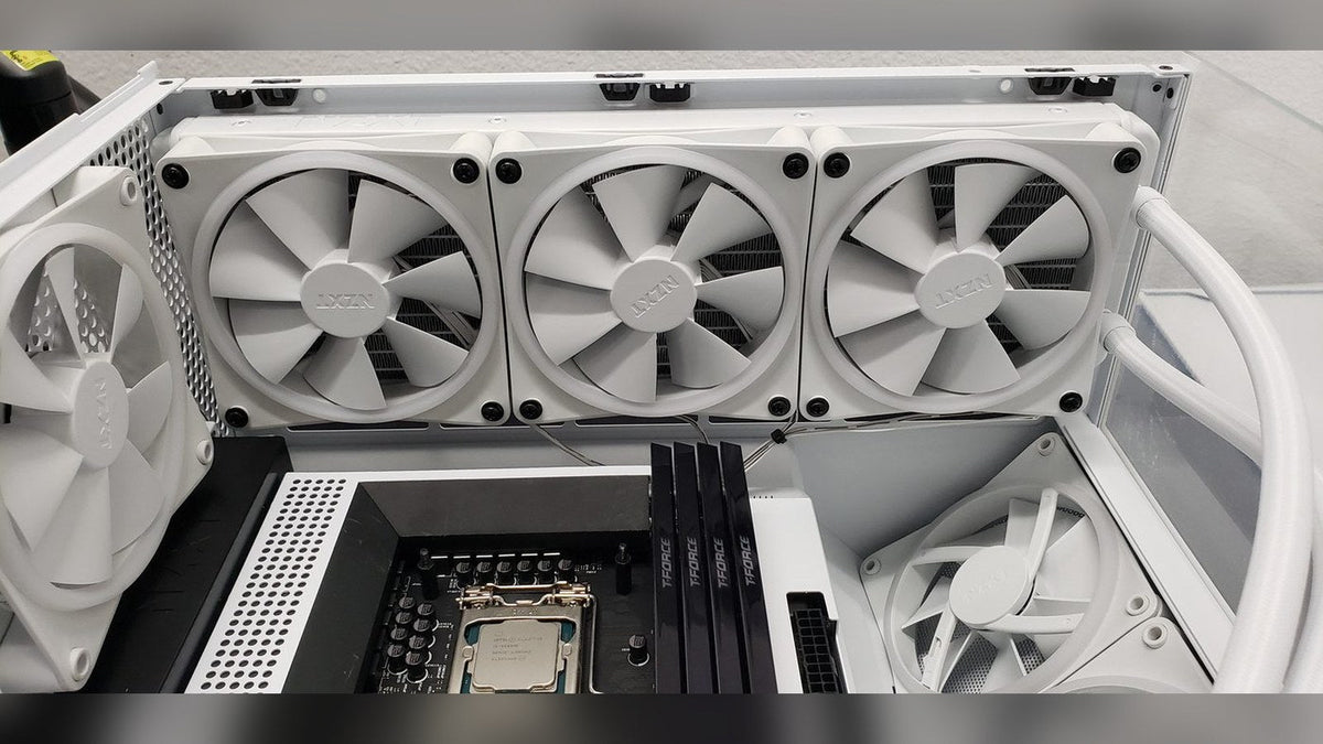 White 360 mm radiator with three white NZXT fans mounted at the top of a white case above the motherboard