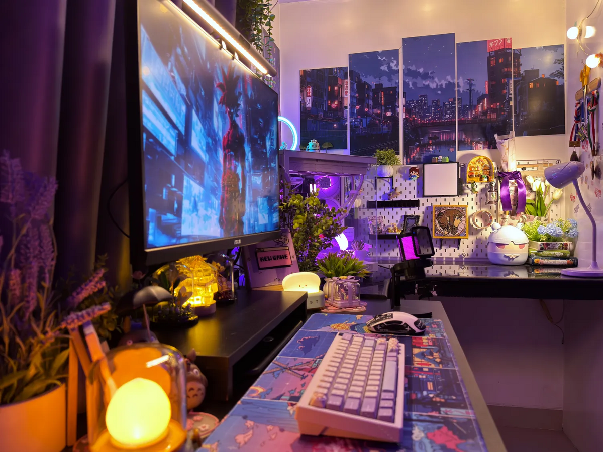 Setups contest winner: a desk with a large monitor, white keyboard, city-art posters, pegboard and purple lighting