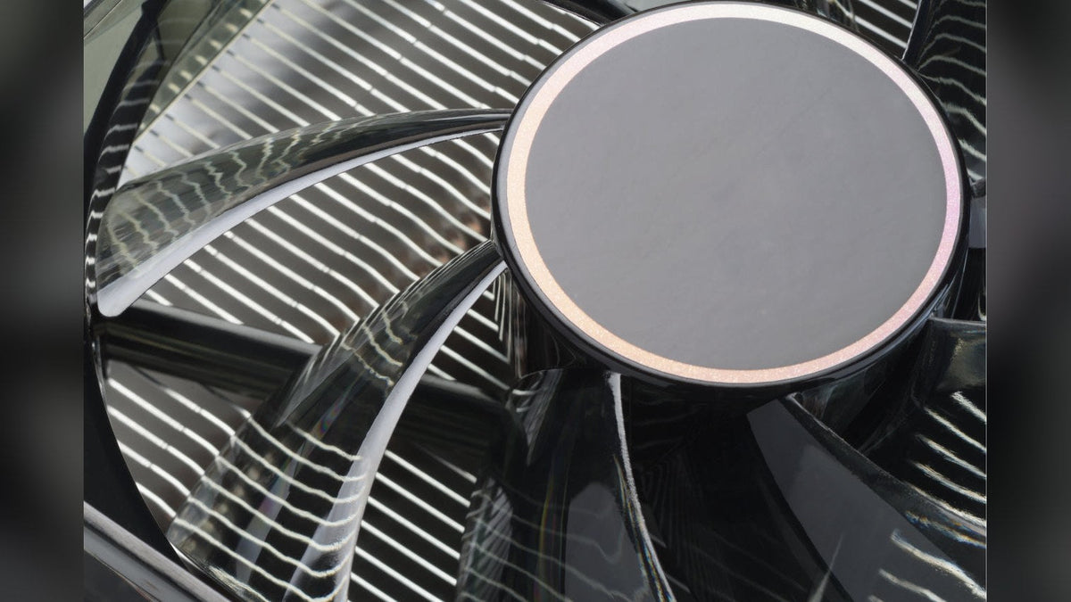 Close-up of a dark cooling fan in front of the aluminum fins of a heatsink