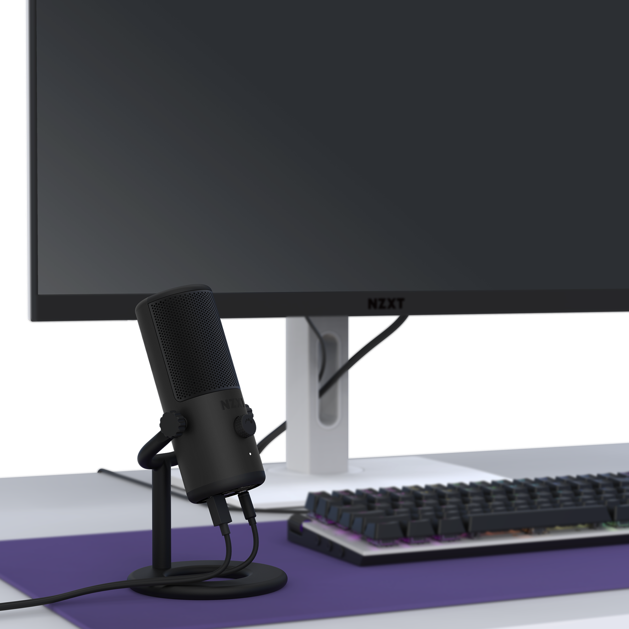 The NZXT Capsule Mini USB microphone on a stand sits beside an RGB keyboard and a large NZXT monitor in a minimalist desk setup, ideal for gaming, streaming, or content creation.
