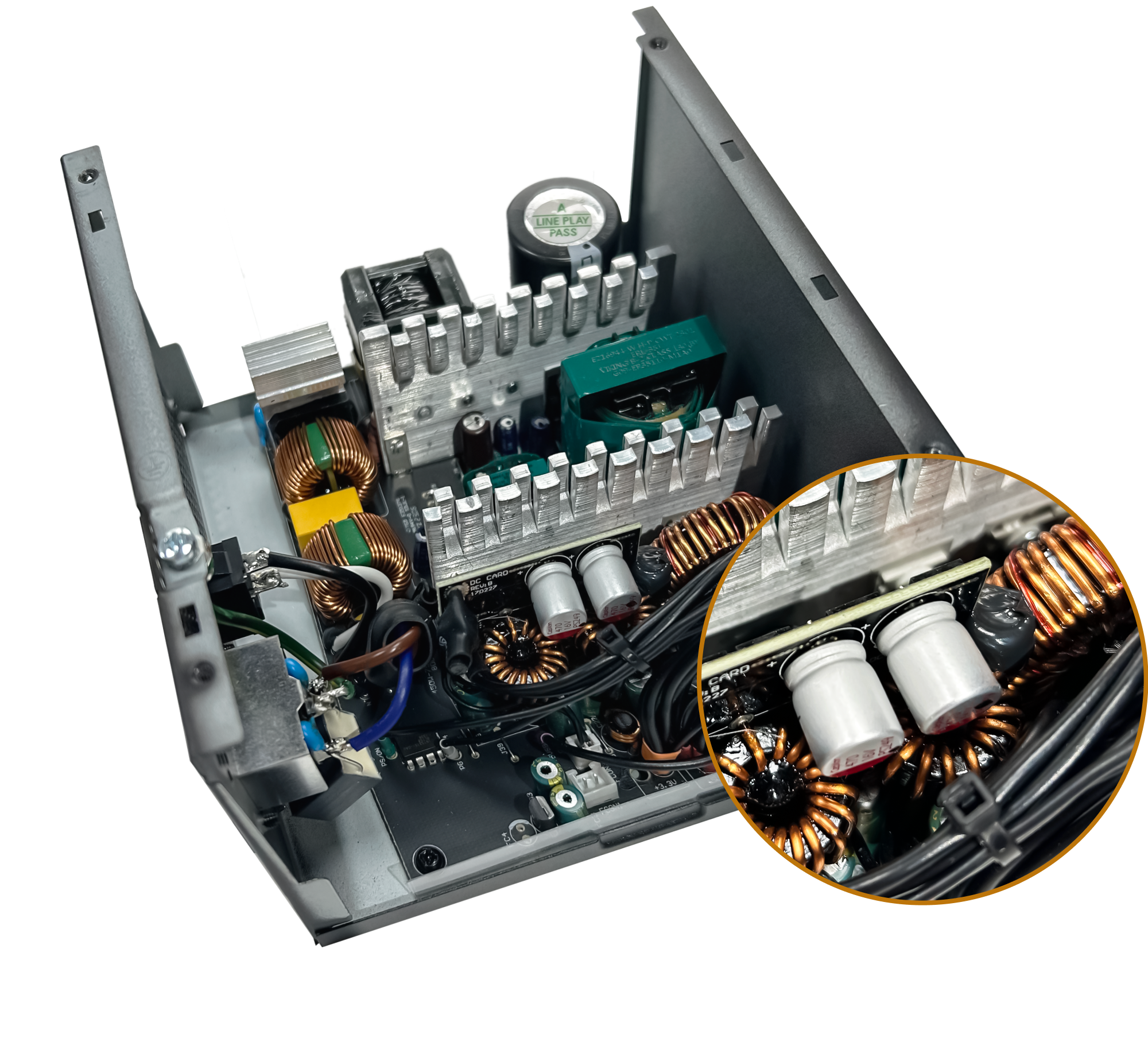 Open computer power supply unit with visible internal components such as capacitors, coils, and heatsinks; a circular inset zooms in on two large capacitors and copper coils for detailed view.